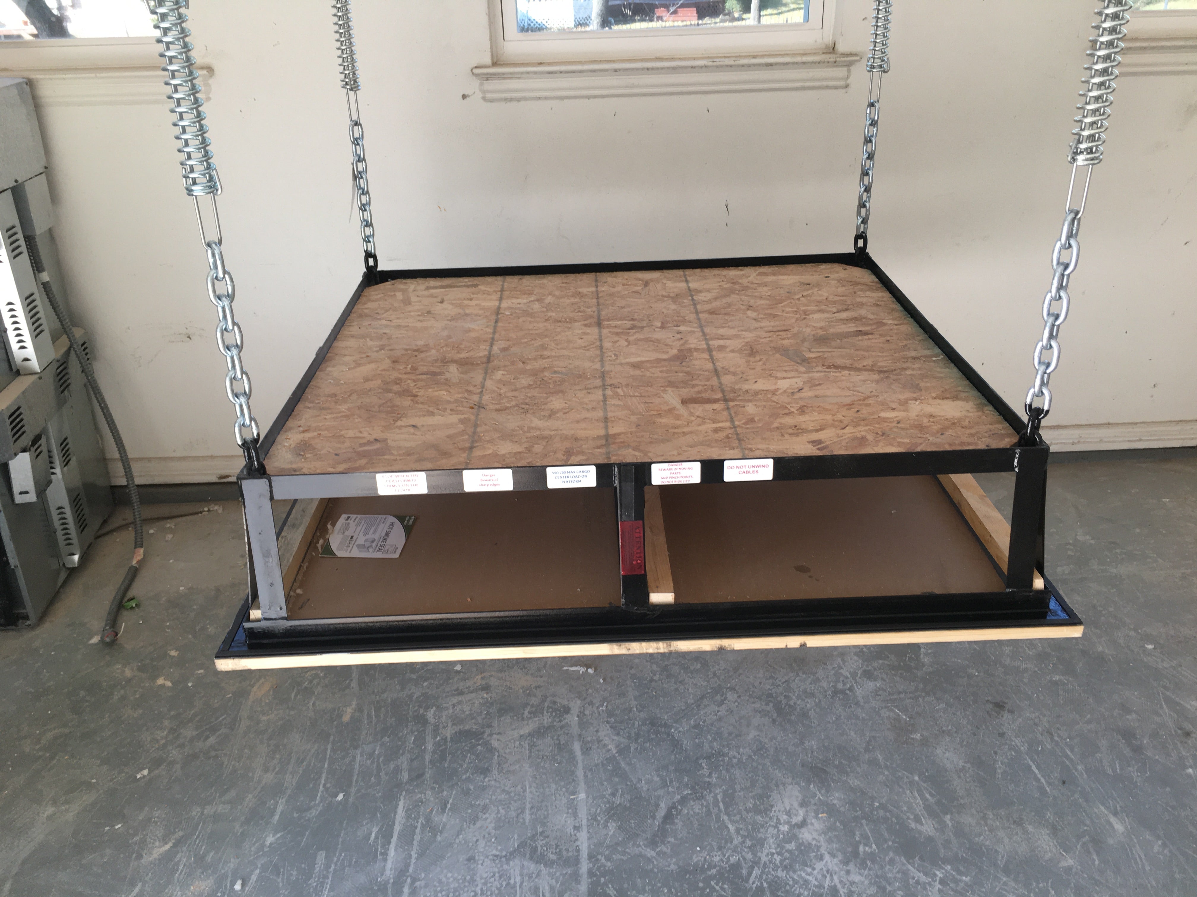 Attic lift platform lowered to floor, suspended by chains and springs