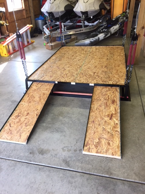 Attic lift with two narrow wooden ramps extended onto garage floor