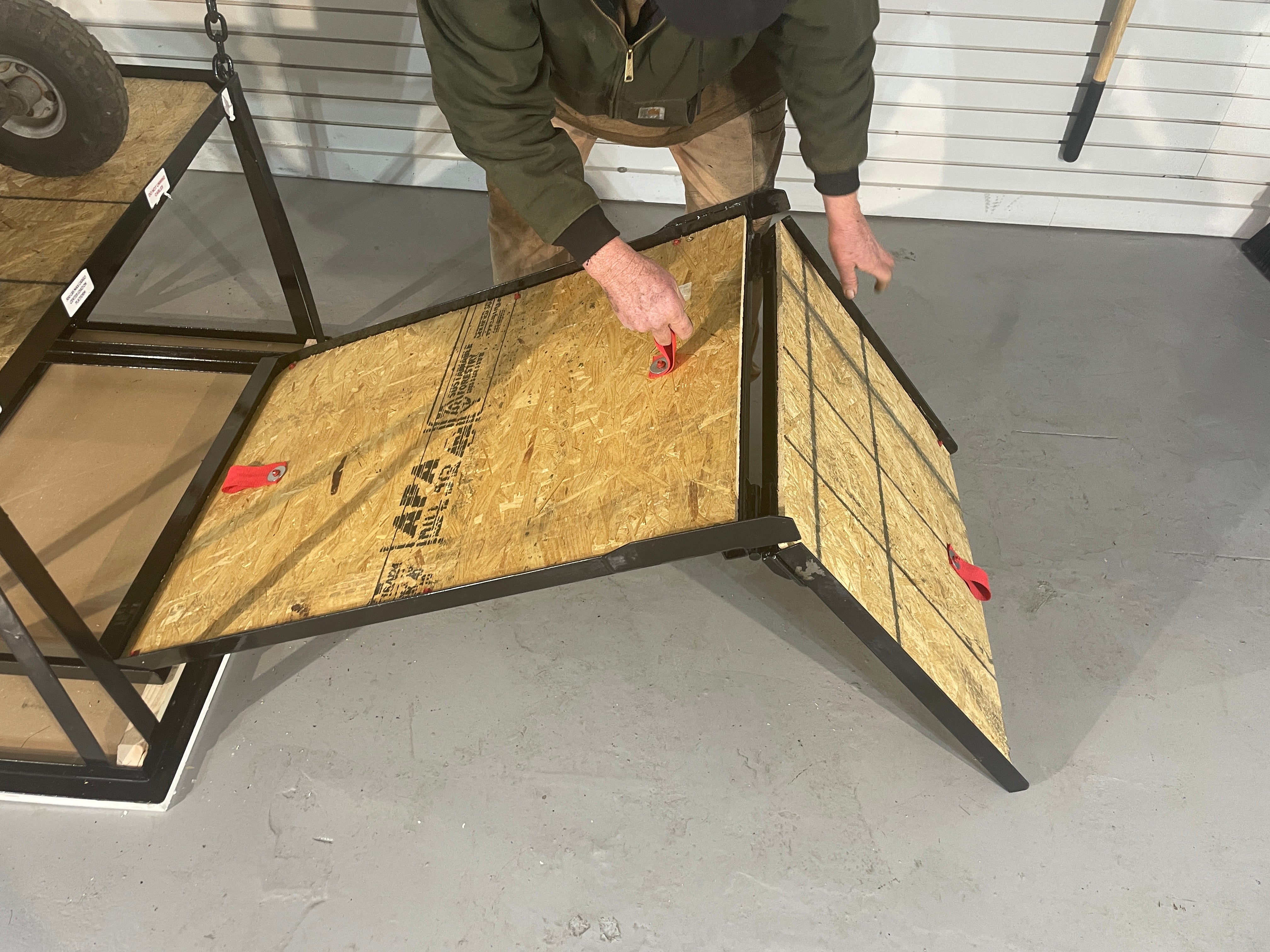 Person unfolding a hinged wooden ramp attached to an attic lift platform