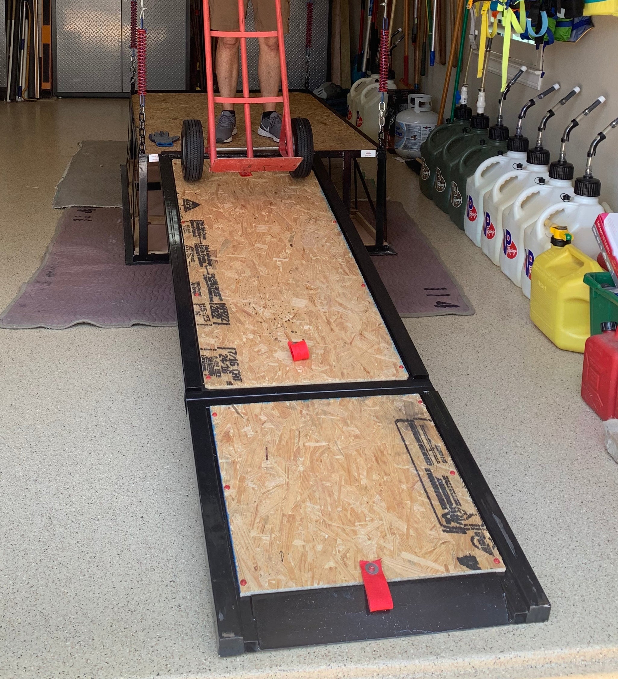 Built-in stow-away ramp extended from attic lift with person using a dolly